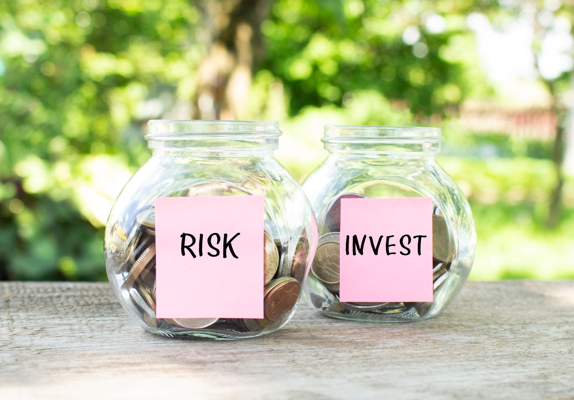 glass-jars-with-coins-inscriptions-risk-invest-stand-wooden-table-investment-budget